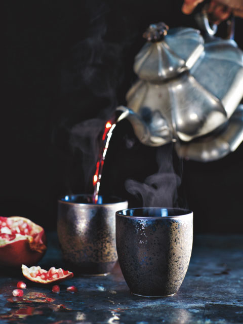tea kettle pouring tea into ceramic cups